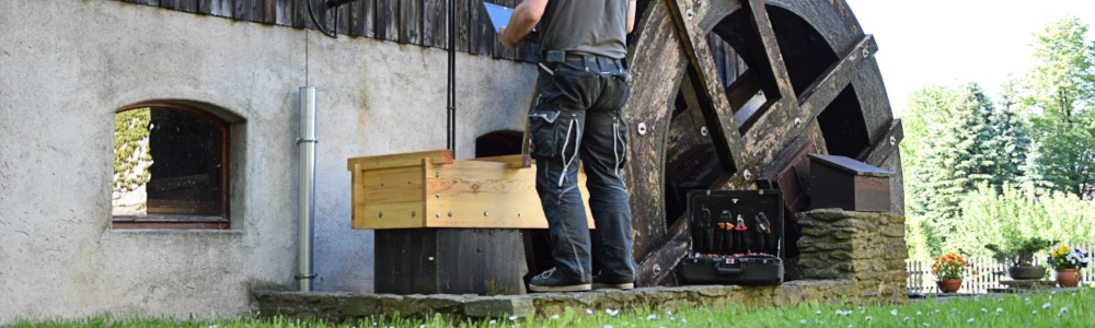 Wasserrad mit Techniker an einem Bach.