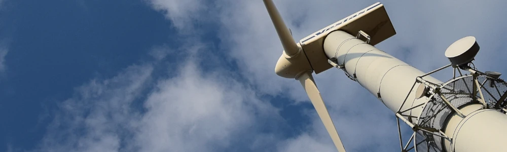 Windkraftanlage mit Mobilfunkantennen auf einem Berg.